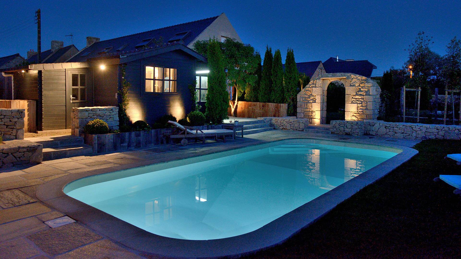 Piscine rectangulaire Sara de nuit sur une terrasse avec éclairages