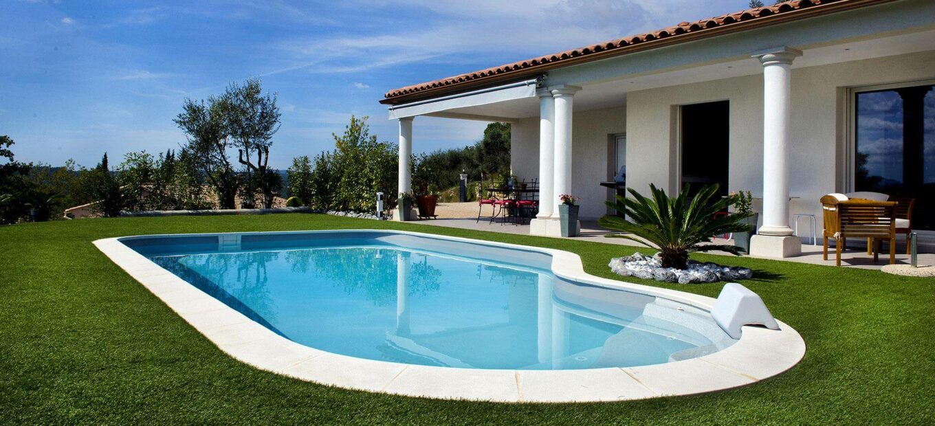 grande Piscine forme libre avec margelles et pelouse synthétique