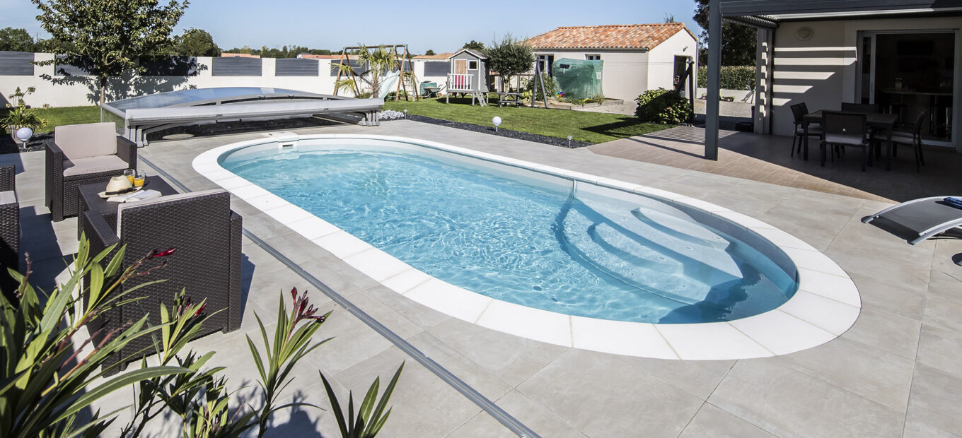 Piscine ovale Elsa dans un jardin avec terrasse en dalles de béton