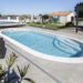 Piscine ovale Elsa dans un jardin avec terrasse en dalles de béton