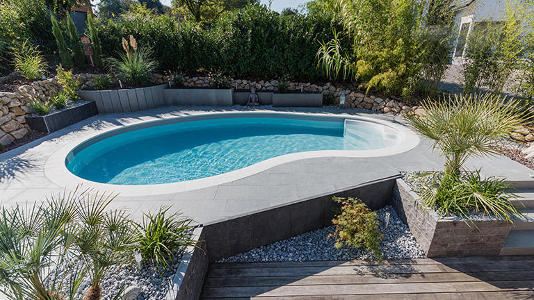 Piscine en forme de haricot avec margelles et escalier entrant