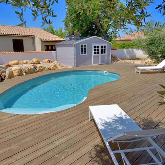 Photo d'une piscine en forme de haricot avec escalier entrant et plage en bois