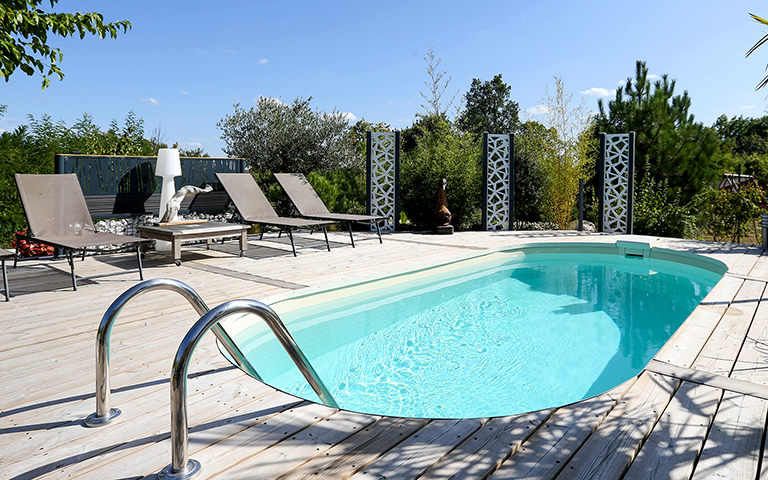 Piscine avec plage bois et margelles pour jouer les contrastes entre les couleurs