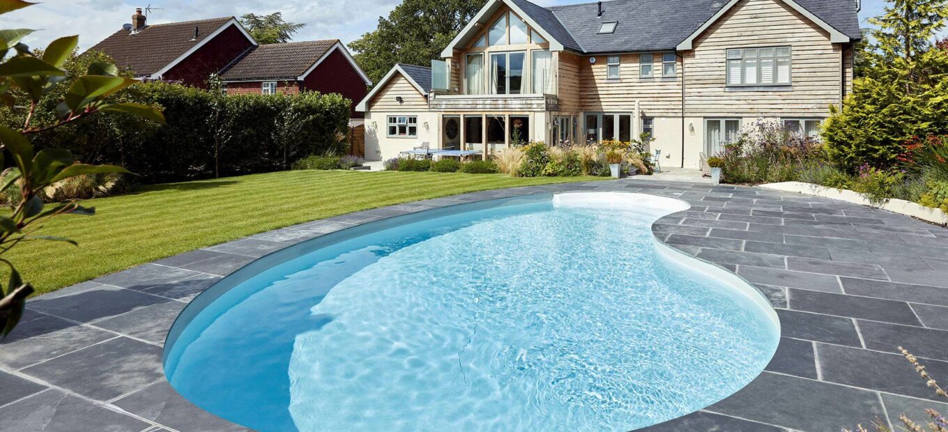 Piscine enterée forme haricot devant maison moderne