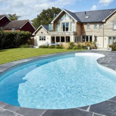 Piscine enterée forme haricot devant maison moderne