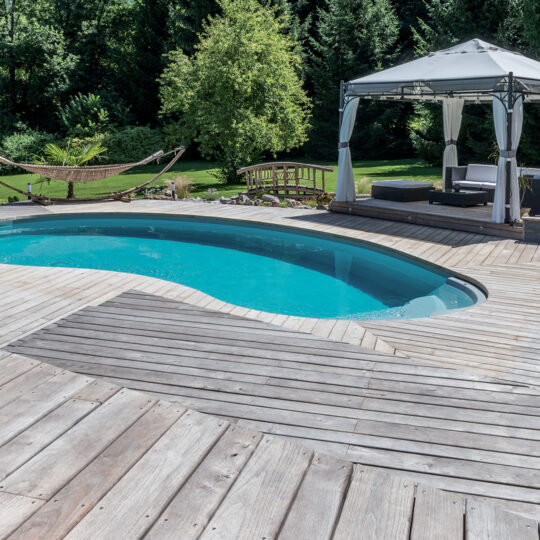 Piscine en forme de haricot avec escalier entrant sur terrasse en bois