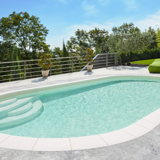 Piscine ovale Elsa dans un jardin avec terrasse en dalles de béton