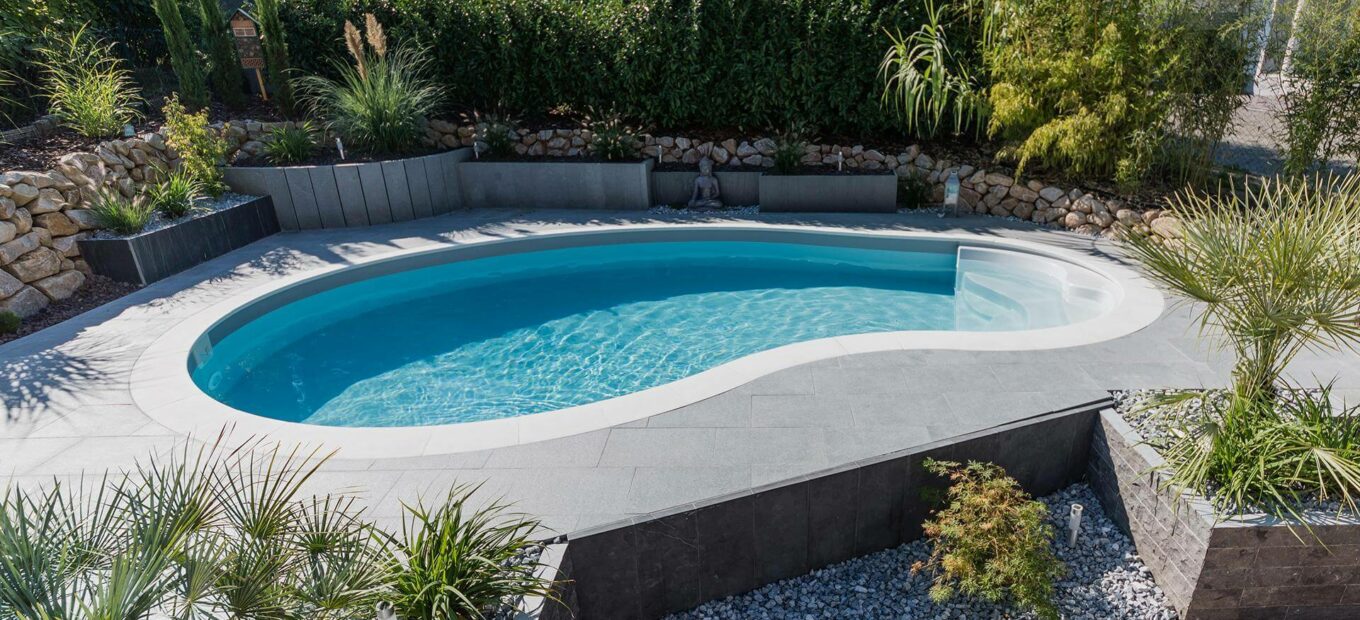 Gartengestaltung mit eingelassenem nierenförmigen Pool und Strand aus Betonplatten