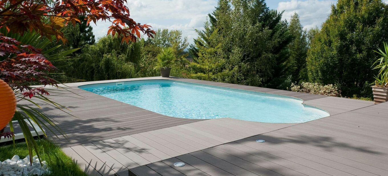 Piscina rettangolare con scale in uscita e area a bordo vasca in legno composito