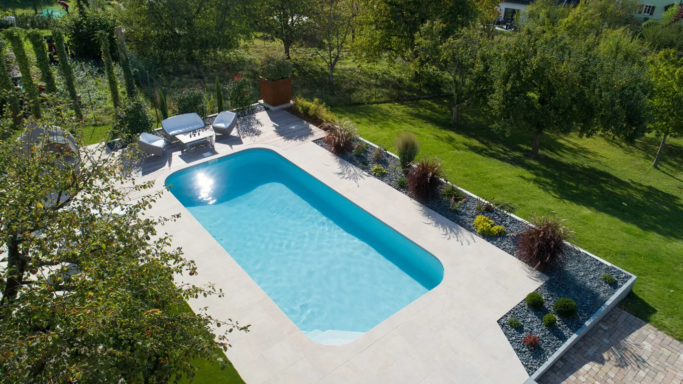 Piscine rectangulaire Sara dans un grand jardin avec dalles en béton