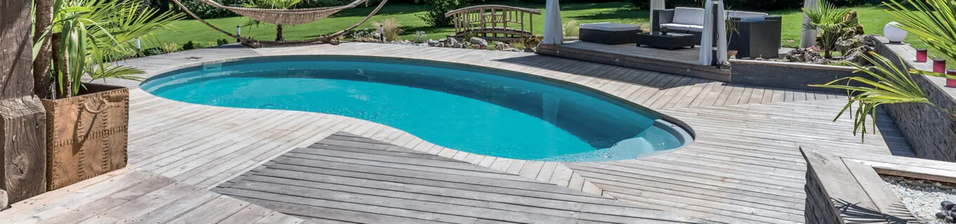 Piscine en forme de haricot avec escalier entrant sur terrasse en bois