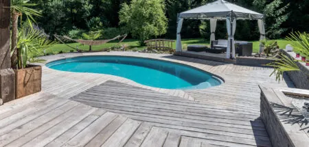 Piscine en forme de haricot avec escalier entrant sur terrasse en bois