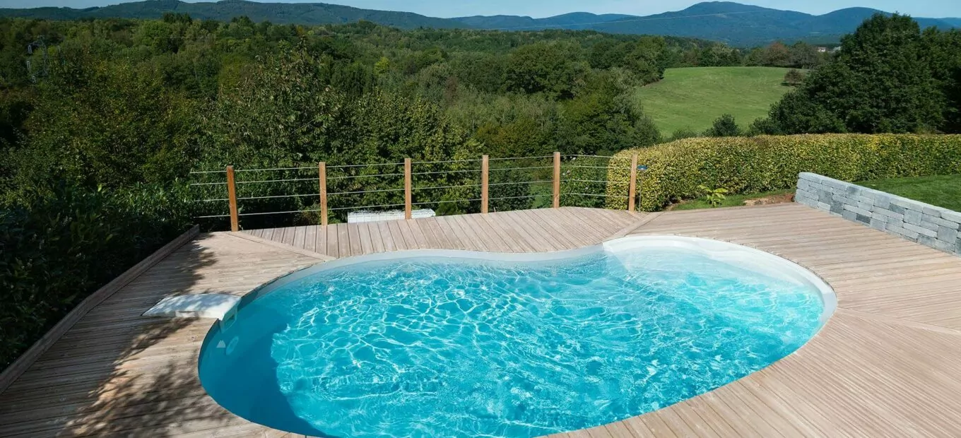 piscina a forma di fagiolo con scale in entrata e area a bordo vasca di legno