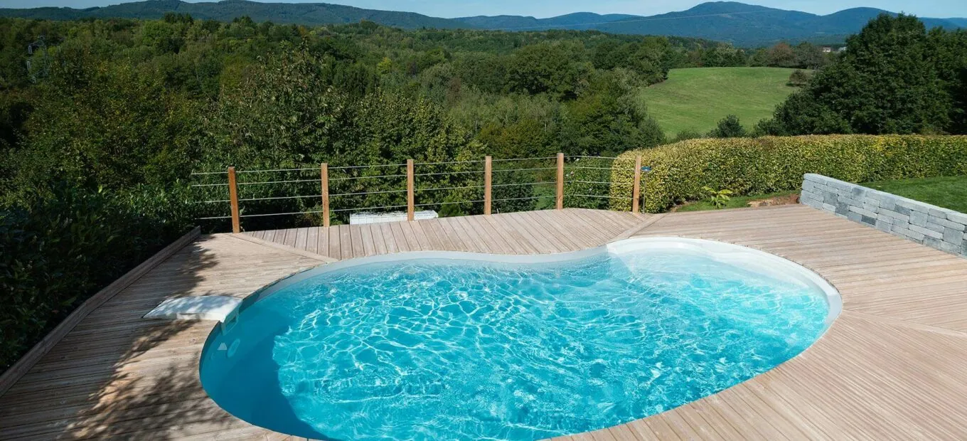 piscina a forma di fagiolo con scale in entrata e area a bordo vasca di legno