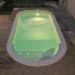 Piscina a forma libera illuminata di notte su una pedana