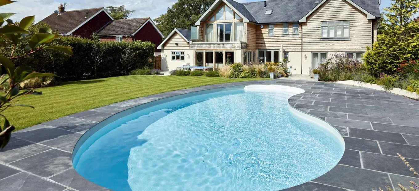 Piscina interrata a forma di fagiolo davanti a casa moderna