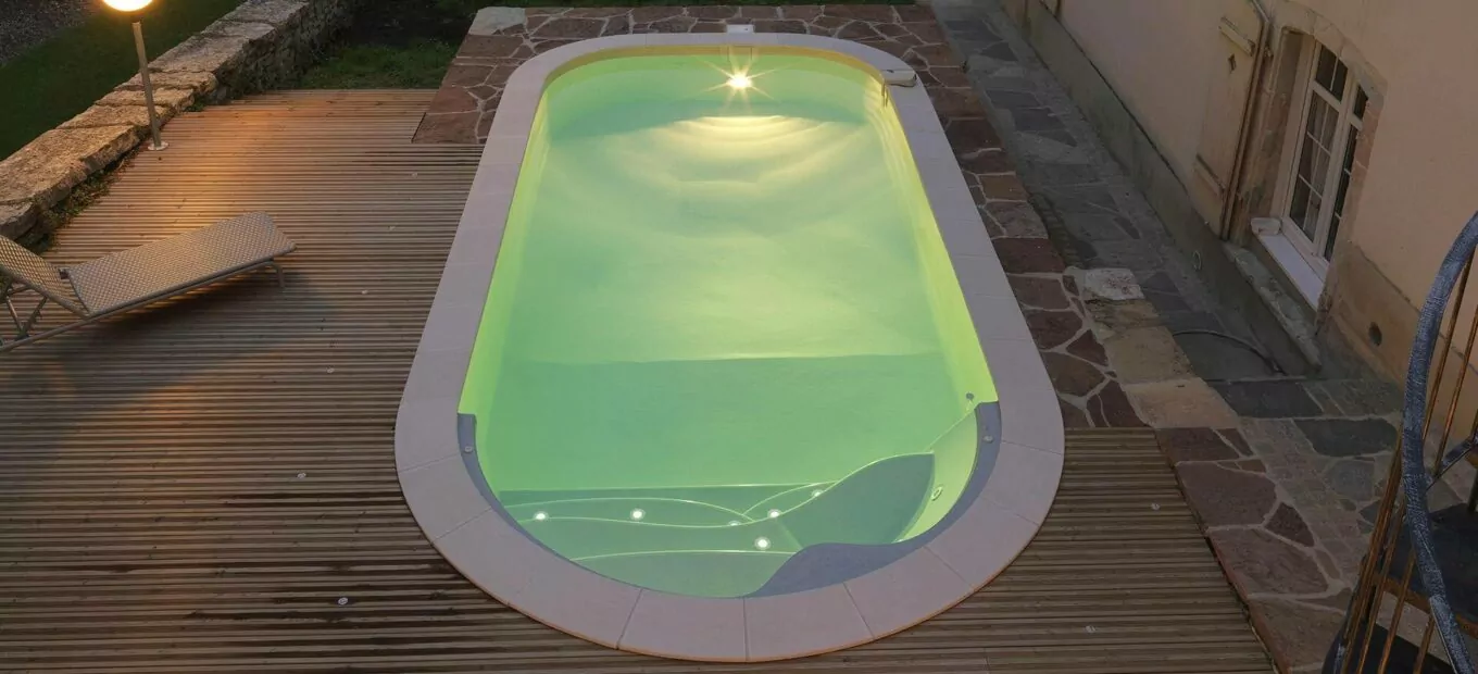 Vrijevorm zwembad met nachtverlichting op een terras